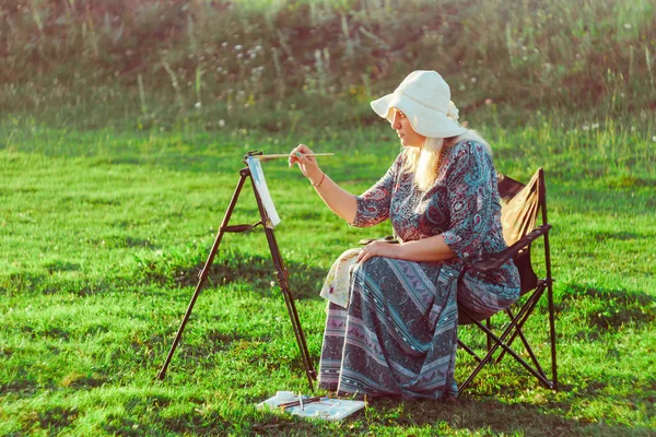 Μια ηλικιωμένη γυναίκα ζωγραφίζει μια εικόνα στη φύση — Φωτογραφία Αρχείου