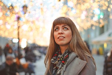 Noel çelenklerinin arkasındaki kız