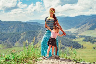 Anne ve kızı dağların arkasında dikiliyorlar.