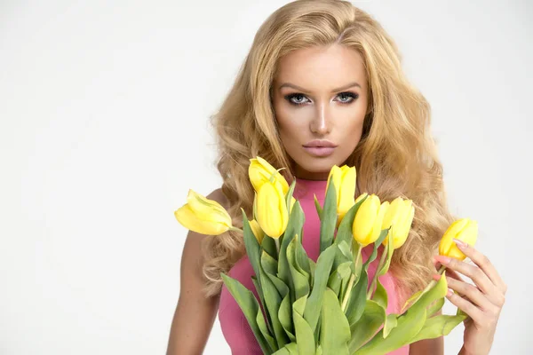 Blond meisje met gele tulpen — Stockfoto