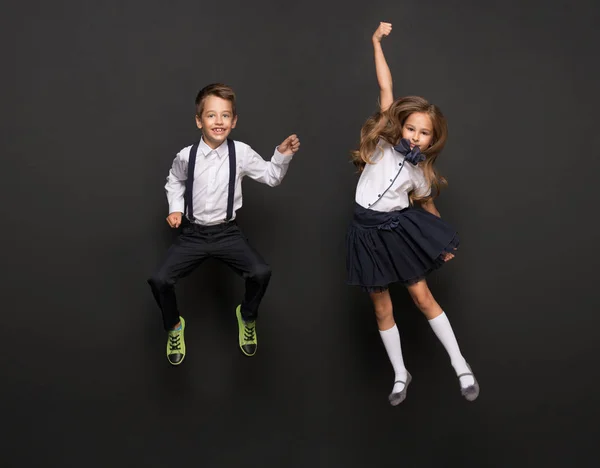 Kinderen gekleed in school uniform springen — Stockfoto