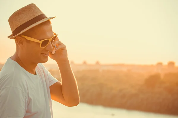 Tipo moderno con sombrero hablando en el teléfono móvil al aire libre — Foto de Stock