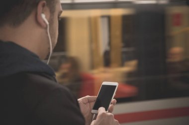 Kentsel adam akıllı telefon ve kulaklık tren istasyonunda kullanma 
