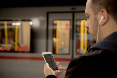 Kentsel adam akıllı telefon ve kulaklık tren istasyonunda kullanma 
