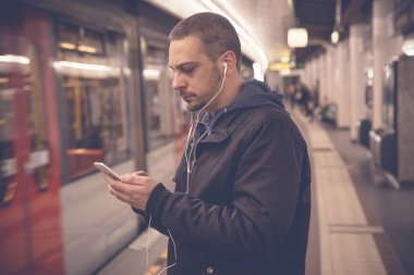 Kentsel adam akıllı telefon ve kulaklık tren istasyonunda kullanma 