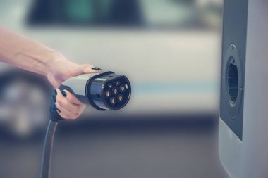 Elektrikli araç şarj cihazı tutan el. Elektrikli arabalar kavramı.  