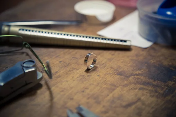 Scrivania per la realizzazione di gioielli artigianali. Prodotto finale della fede nuziale sul tavolo . — Foto Stock