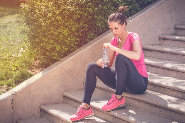 Jogger sitter på trappan och hålla flaska vatten — Stockfoto