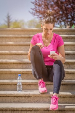 Merdivenlerde oturan ve smartphone kullanarak koşucu 