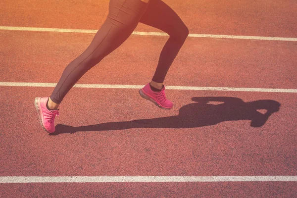 Primer plano de las piernas de jogger femeninas corriendo en pista atlética —  Fotos de Stock