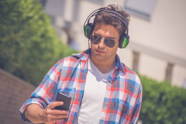 Yürüyüş ve h ile müzik dinlemek için bir akıllı telefon kullanarak mutlu adam