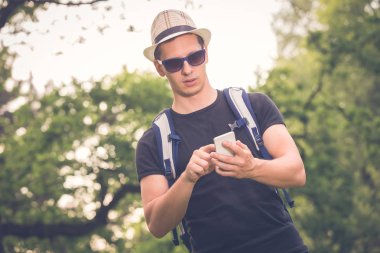 Doğanın içinde smartphone bakarak genç turist adam portresi