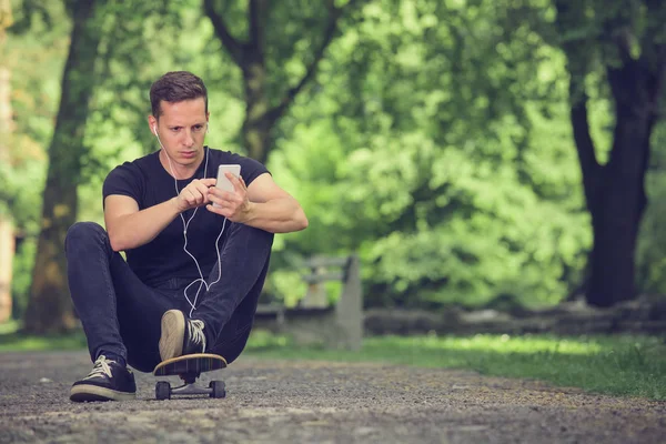 Skateboardista poslech hudby ze smartphonu — Stock fotografie