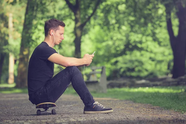 Skateboarder ouvir música do smartphone — Fotografia de Stock