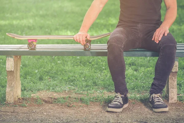 Skateboarder sitting on bench in the park — Stock Photo, Image