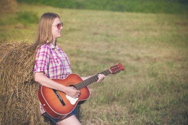 Çayır üzerinde akustik gitar çalmak kadın portresi. Countr