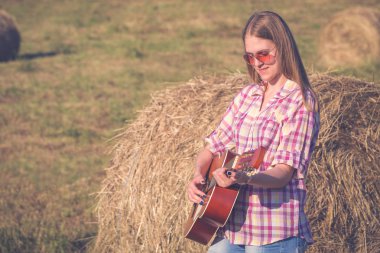 Çayır üzerinde akustik gitar çalmak kadın portresi. Countr