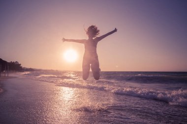 Gün batımında sahilde atlama erkek