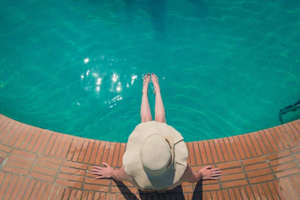Hermosa mujer en un sombrero sentado en el borde de la caca de natación — Foto de Stock