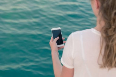Boş ekran smartphone karşı mavi okyanus su tutan kadın 
