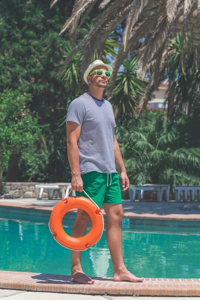 Modieuze man permanent aan de rand van het zwembad en holdin — Stockfoto