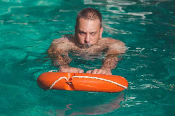 Человек плавает с помощью спасательного буя — стоковое фото