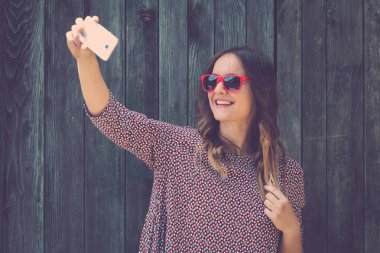 Genç erkek ile smartphone ahşap duvar karşı selfie alarak