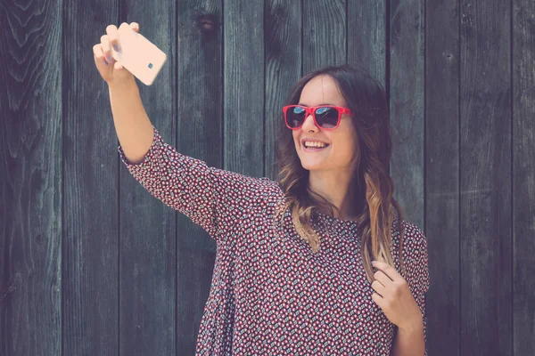 Genç erkek ile smartphone ahşap duvar karşı selfie alarak