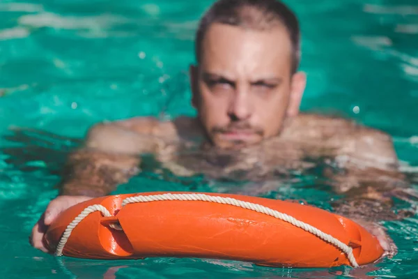 Человек плавает с помощью спасательного буя — стоковое фото