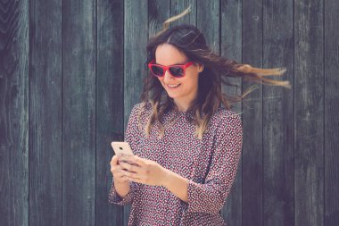 Ahşap duvar karşı smartphone kullanarak genç erkek portresi