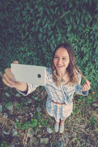 Beautiful female taking selfie with smartphone outdoors — Stock Photo, Image