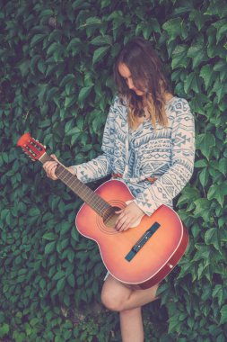 Erkek yaprak yeşil duvar arka planı gitar çalmak