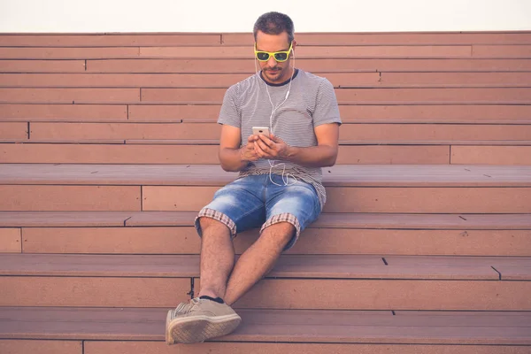 Junger Mann sitzt auf Treppe und benutzt Smartphone — Stockfoto