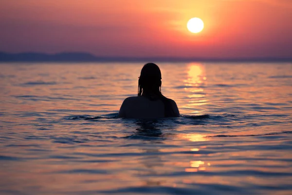 Kobieta w ocean o zachodzie słońca — Zdjęcie stockowe