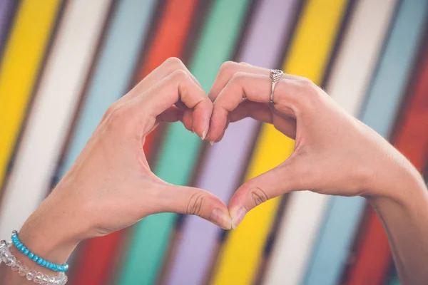 Руки у формі серця на барвистому фоні — стокове фото