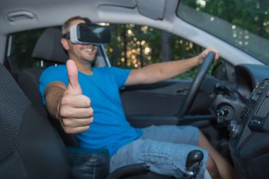 Arabada oturan ve thum gösteren sanal gerçeklik gözlüklü adam