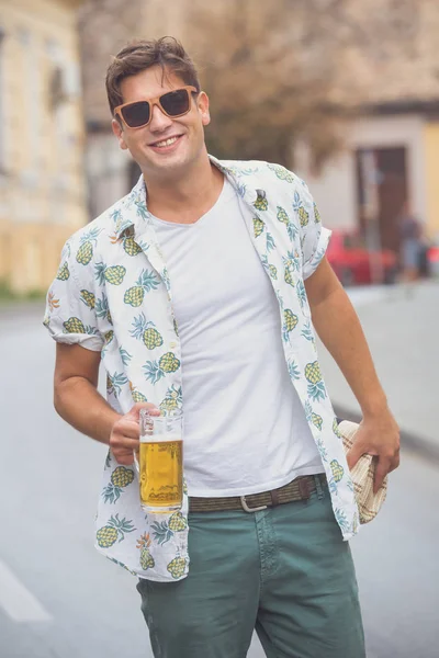 Jeune homme à la mode marchant dans la rue et tenant de la bière — Photo