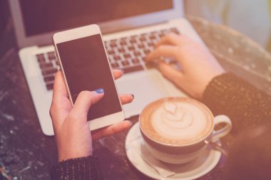 T kahve tadını çıkarırken smartphone ve dizüstü bilgisayar kullanan kadın