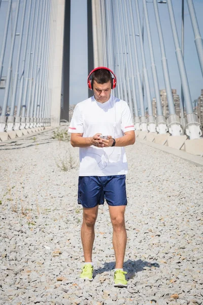 Jogger com smartphone e fones de ouvido na ponte — Fotografia de Stock