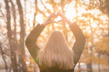 Kız kalp şekli elleri açık havada günbatımında yapma 