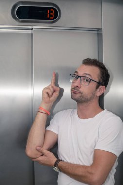 Endişeli adam asansörde on üç katta. Kötü şans kavramı.