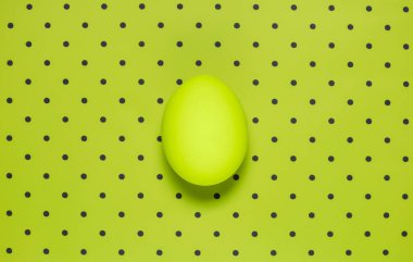 Düz bir yeşil renkli yumurta parlak yeşil polka zemin üzerinde yatıyordu