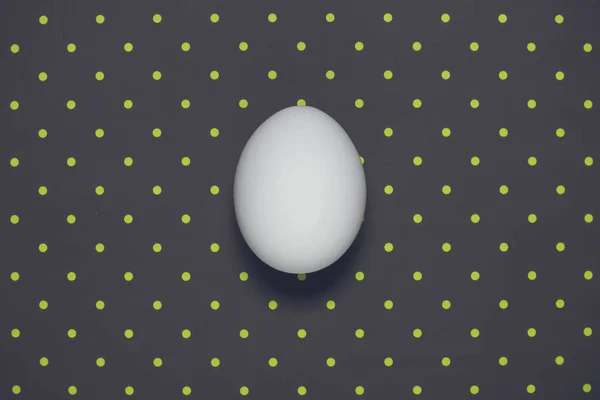 Puesta plana de un huevo sobre fondo oscuro de polka —  Fotos de Stock