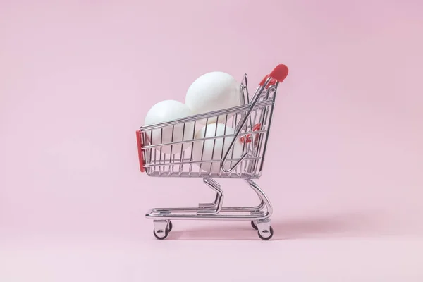 Яйца в маленькой корзине на розовом фоне . — стоковое фото