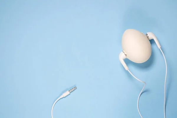 Music style egg with earphones flat lay against pastel blue background. — Stock Photo, Image