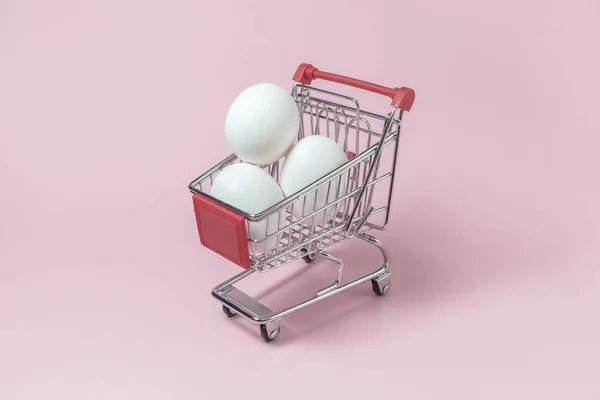 Яйца в маленькой корзине на розовом фоне . — стоковое фото