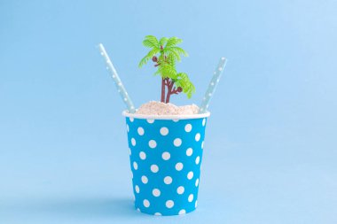 Kağıt bardak ıssız bir ada ve payet seyahat kavramı içme ile.