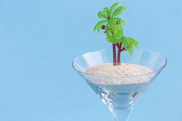 Copo de cocktail cheio de areia e palmeira pequena. Praia e ilha criativo conceito minimalista . — Fotografia de Stock