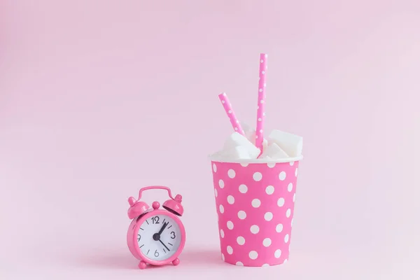 Будильник и бумажная чашка с кубиками сахара и соломинки для питья изолированы на розовом фоне творческой пищи минималистская концепция — стоковое фото
