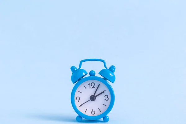 Small alarm clock on blue background — Stock Photo, Image